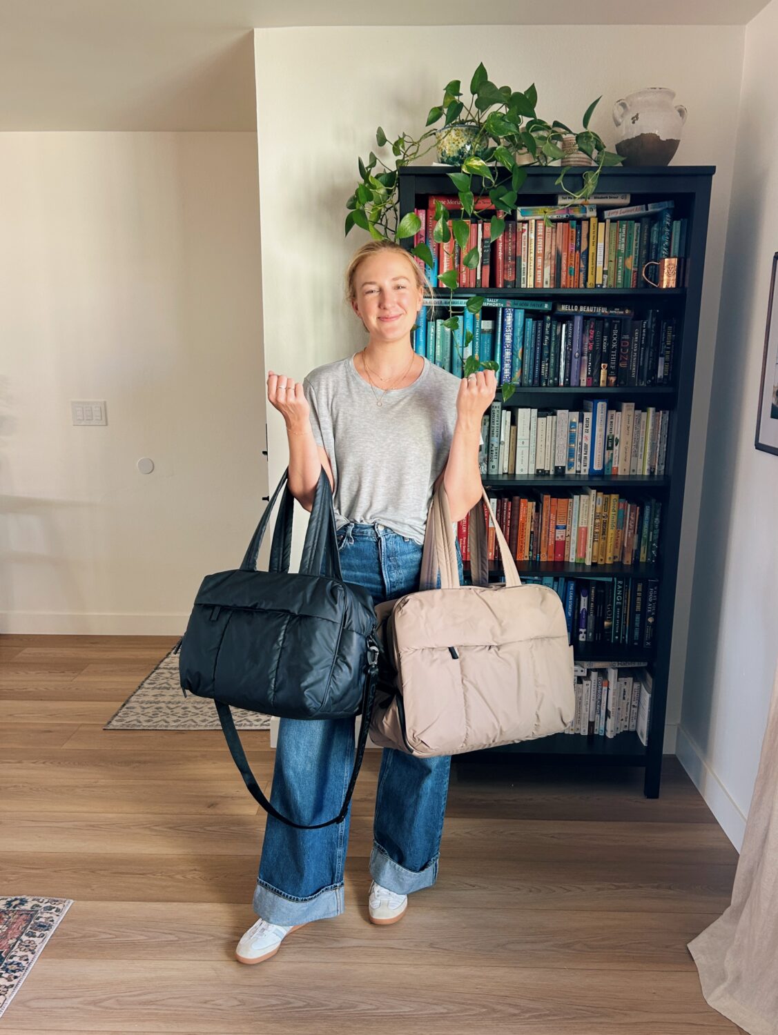 ruth nuss holding the calpak luka duffel and the large luka duffel to comare sizes for her calpak luka duffel review