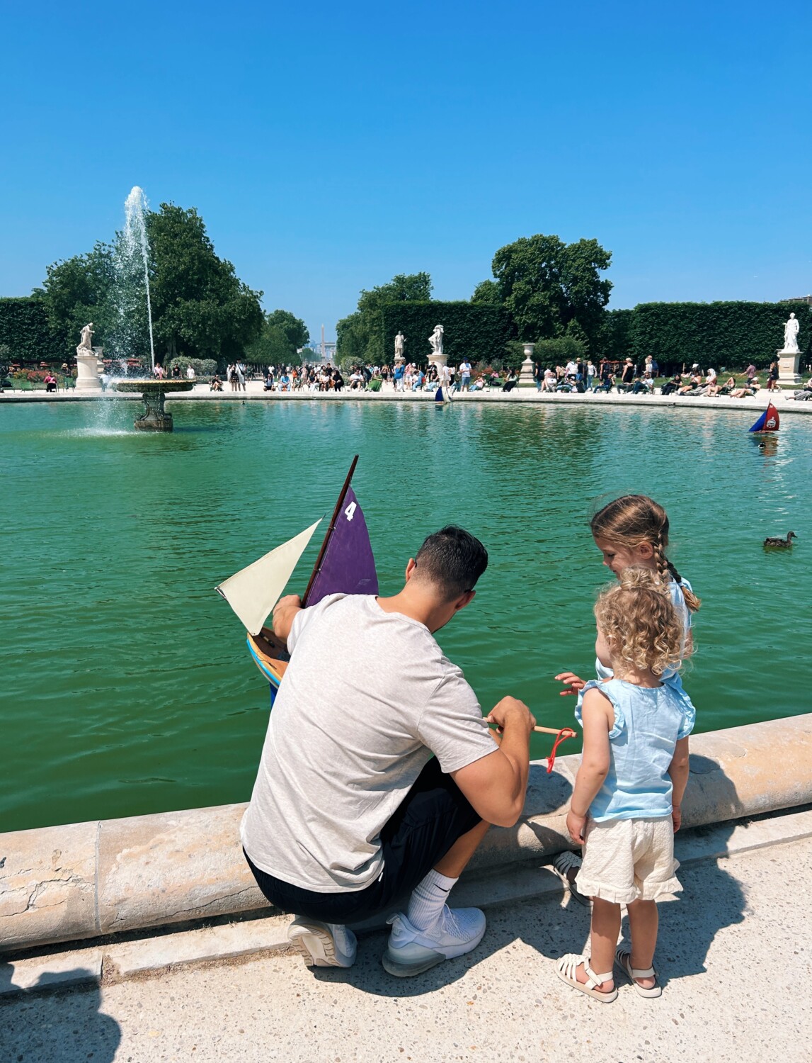 dad with her two kids playing at the fountain 