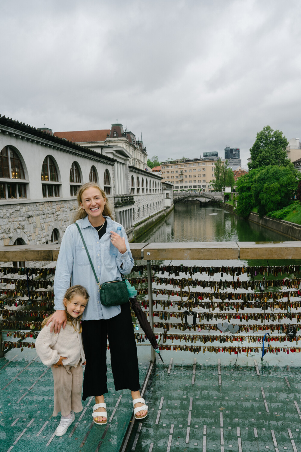 woman with her child standing at a bridge with locks 