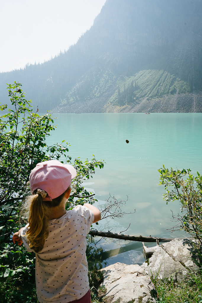 kid throwing a stone in the lake during their Banff Family Travel