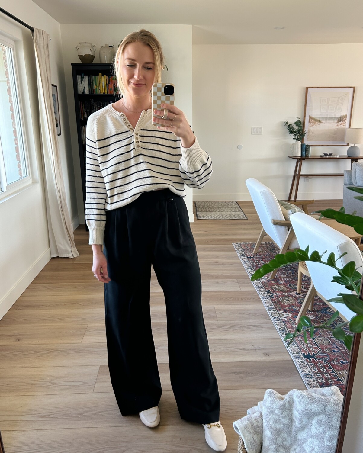 Ruth Nuss wearing her Sézane Léontine Jumper with black trousers and white mules. 