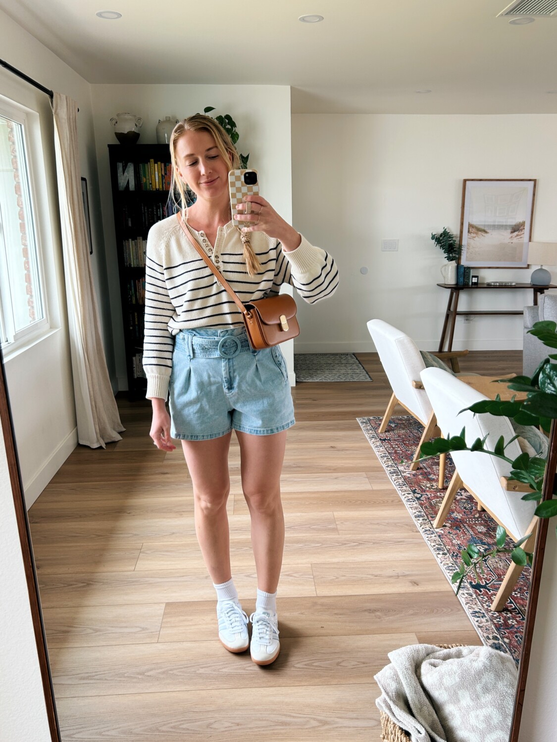 Ruth Nuss wearing her Sézane Léontine Jumper with belted denim shorts and tennis shoes. 