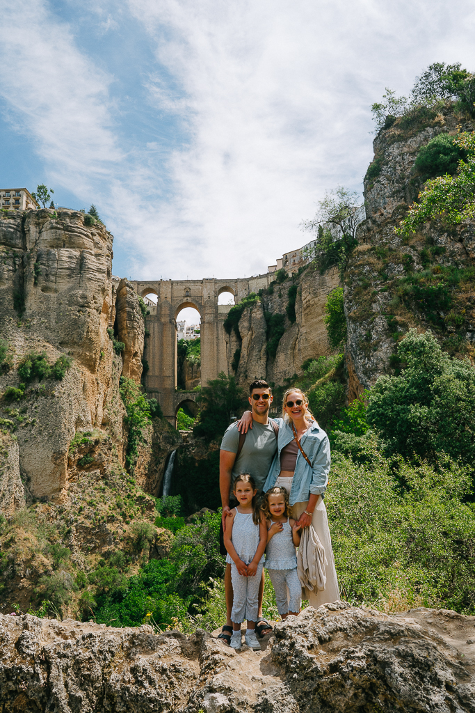 Ruth Nuss family in front of the old bridge and waterfall in Ronda Spain for their 2 week Spain and Portugal itinerary with kids