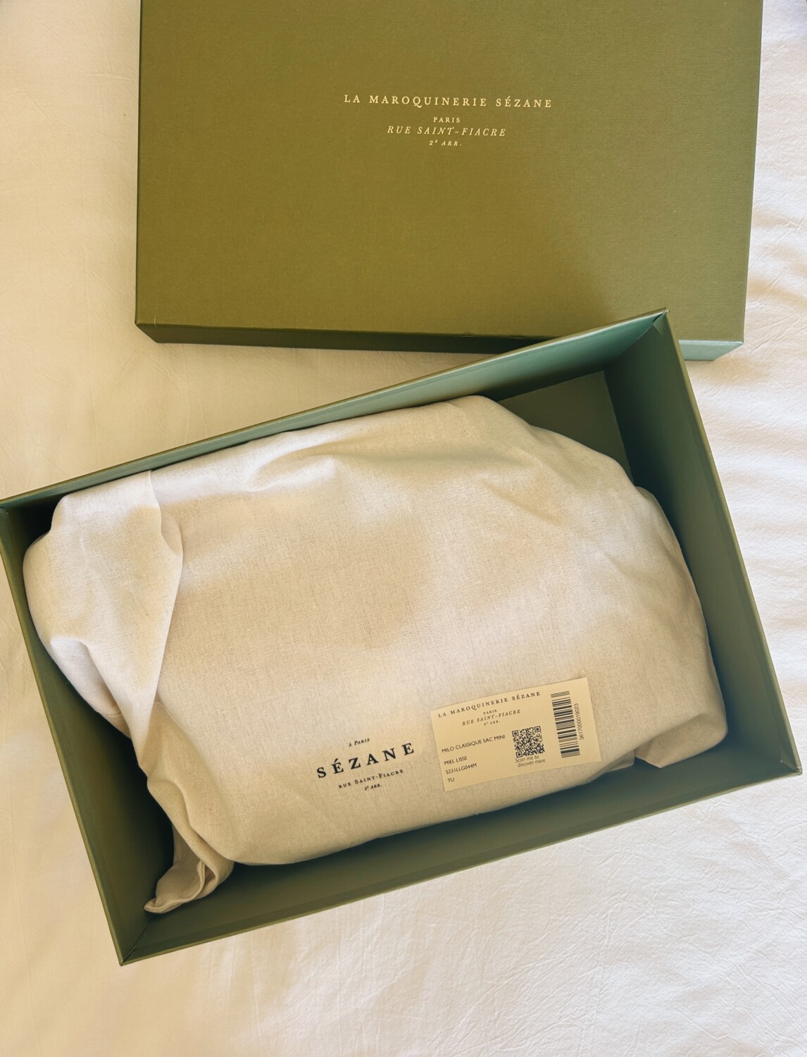 a green cardboard box with a cream colored dust bag