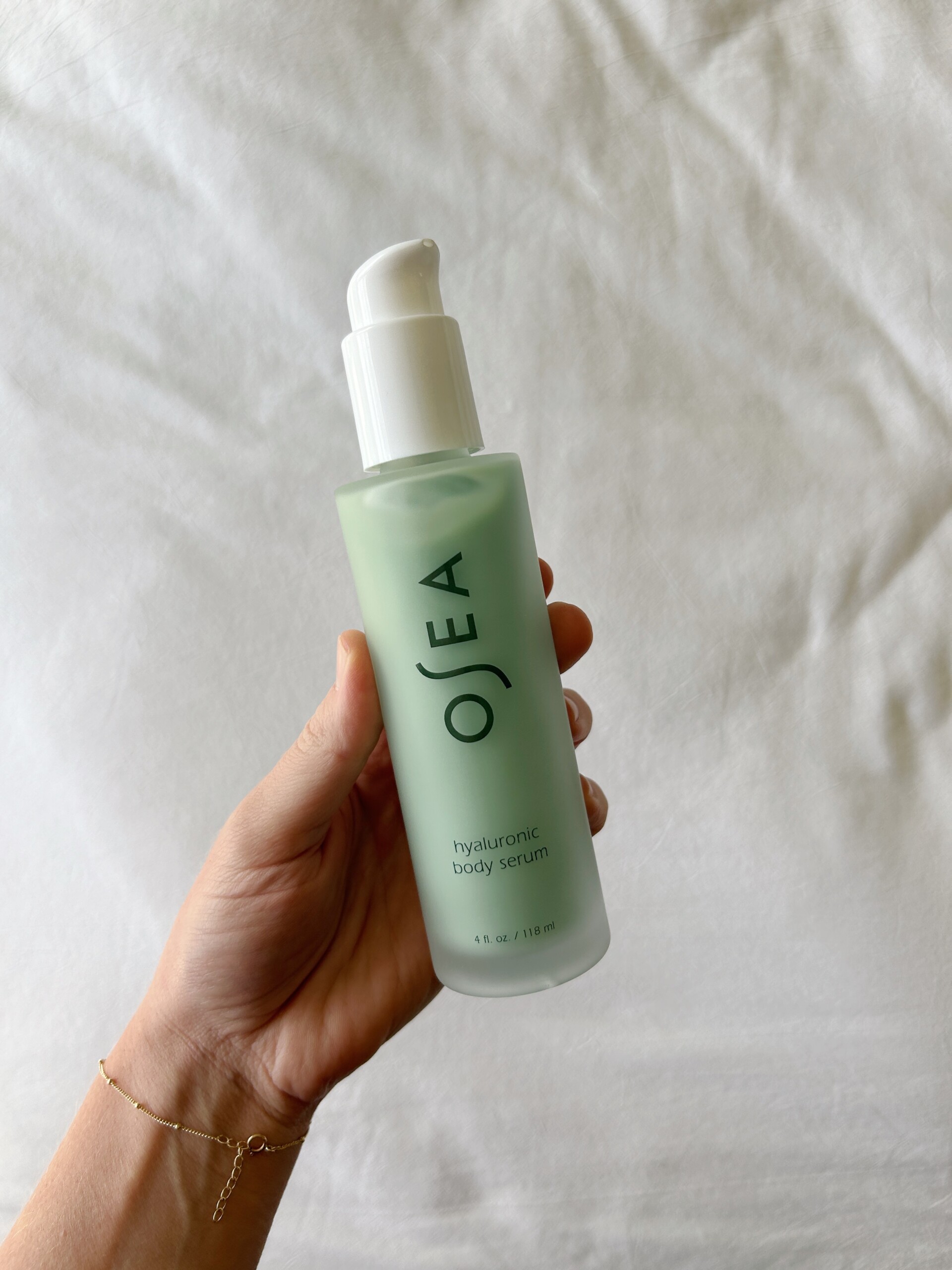 Hand holding a bottle of Osea Hyaluronic Body Serum