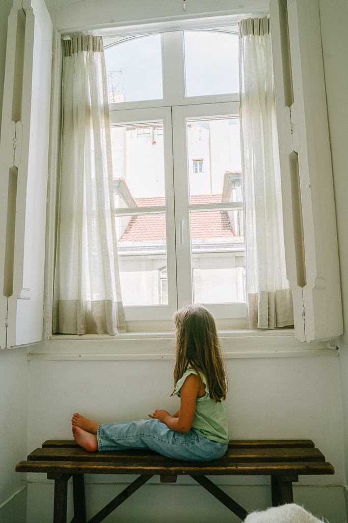 girl sitting in a window in an apartment hotel in lisbon portugal