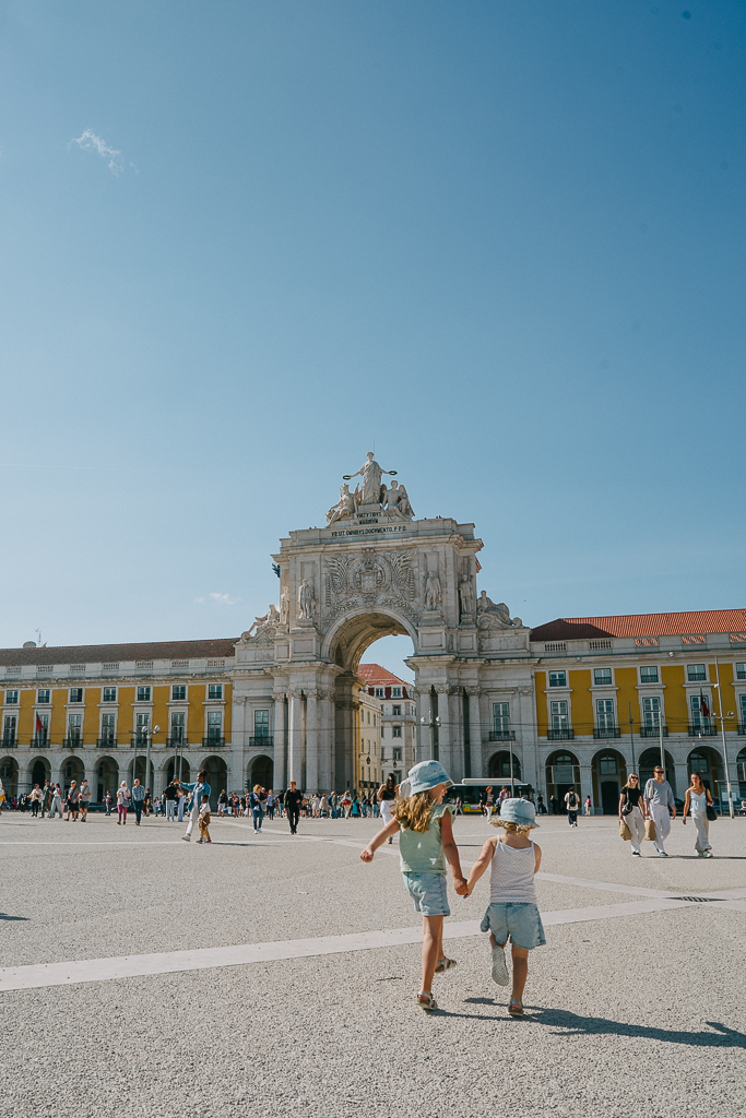 two girls running in Praça do Comércio in Lisbon, Portugal
