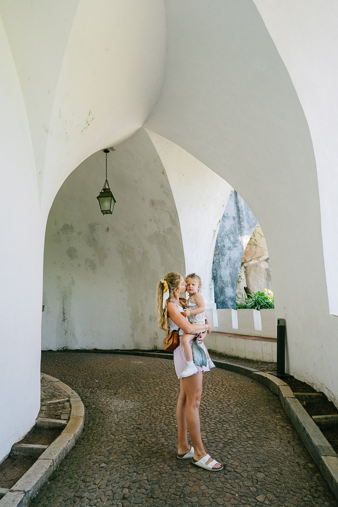 ruth nuss and her daughter in an arched white walkway in pena palace in sintra