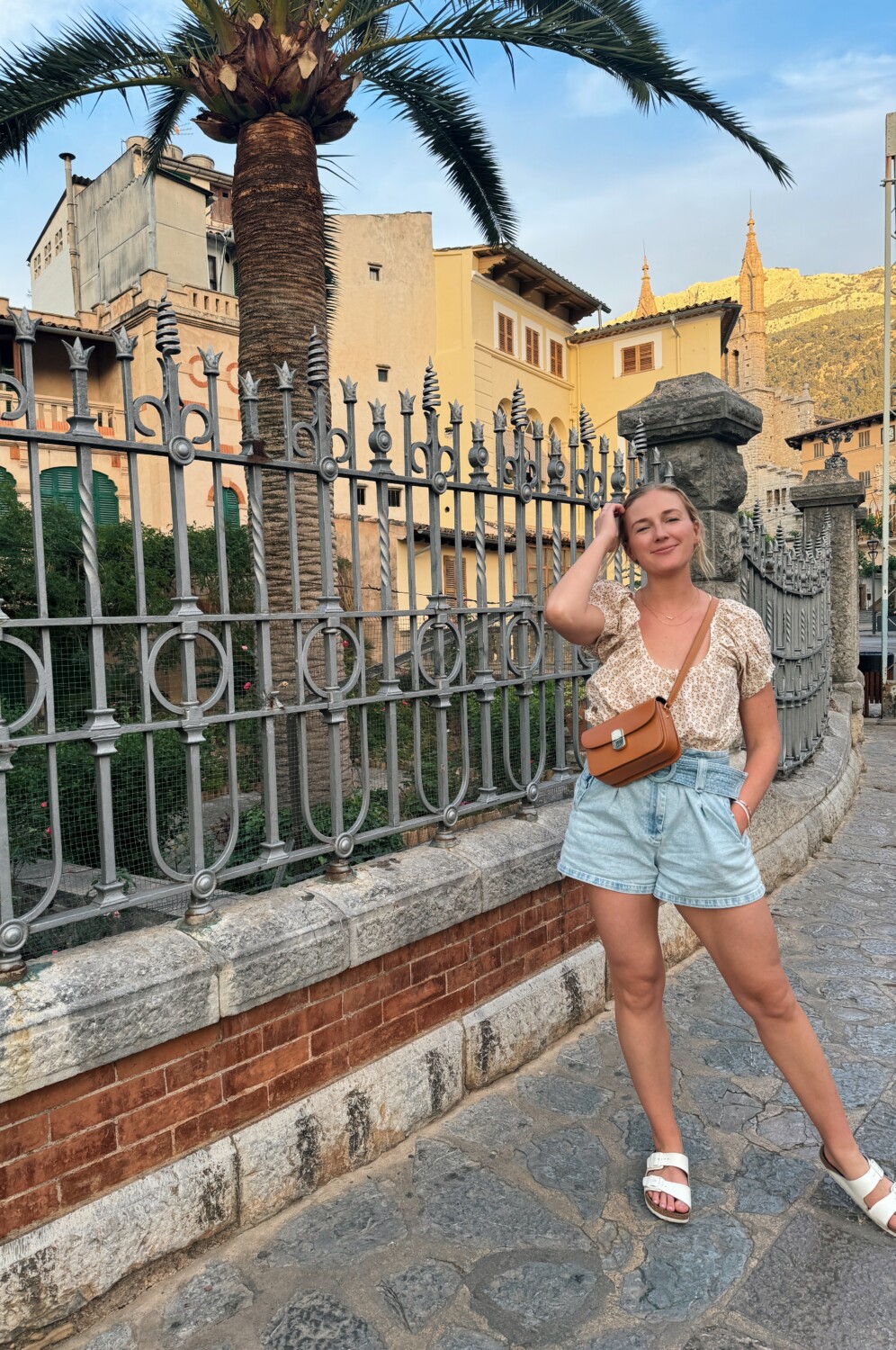 Ruth Nuss wearing belted denim shorts and afloral top in Soller, Mallorca