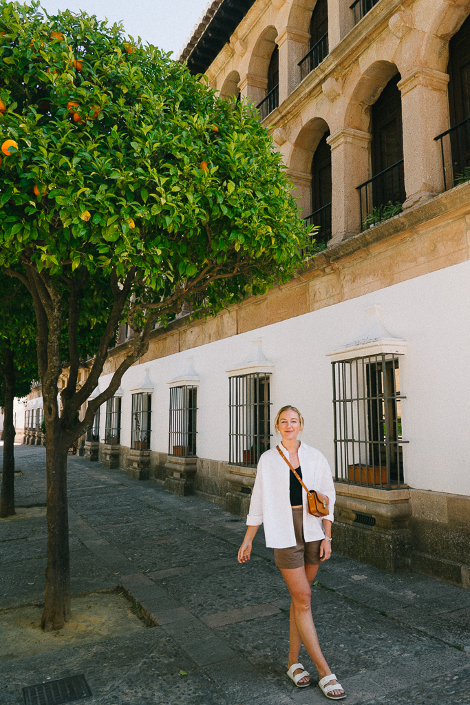 Ruth Nuss standing by a citrus tree and an old building in Ronda, Spain