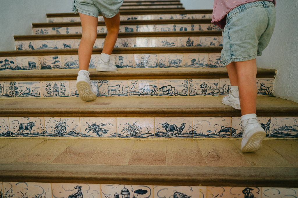 a closeup of two girls walking up stairs with tiles painted with bulls at the ronda bull ring