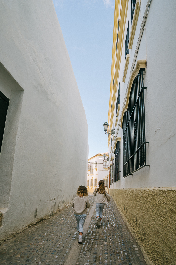 two girls running in a small street in ronda spain