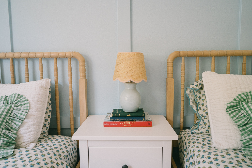 light blue lamp on a nighstand between two twin beds for girls