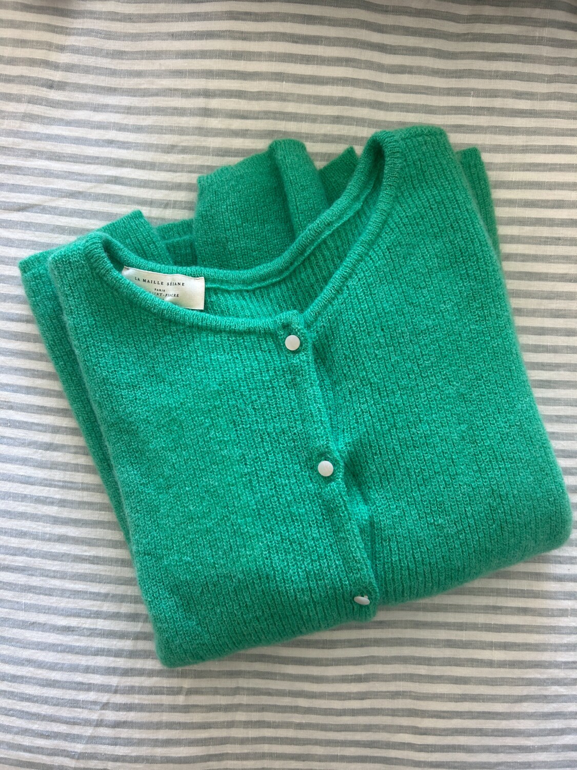 sezane gaspard cardigan folded on a bed