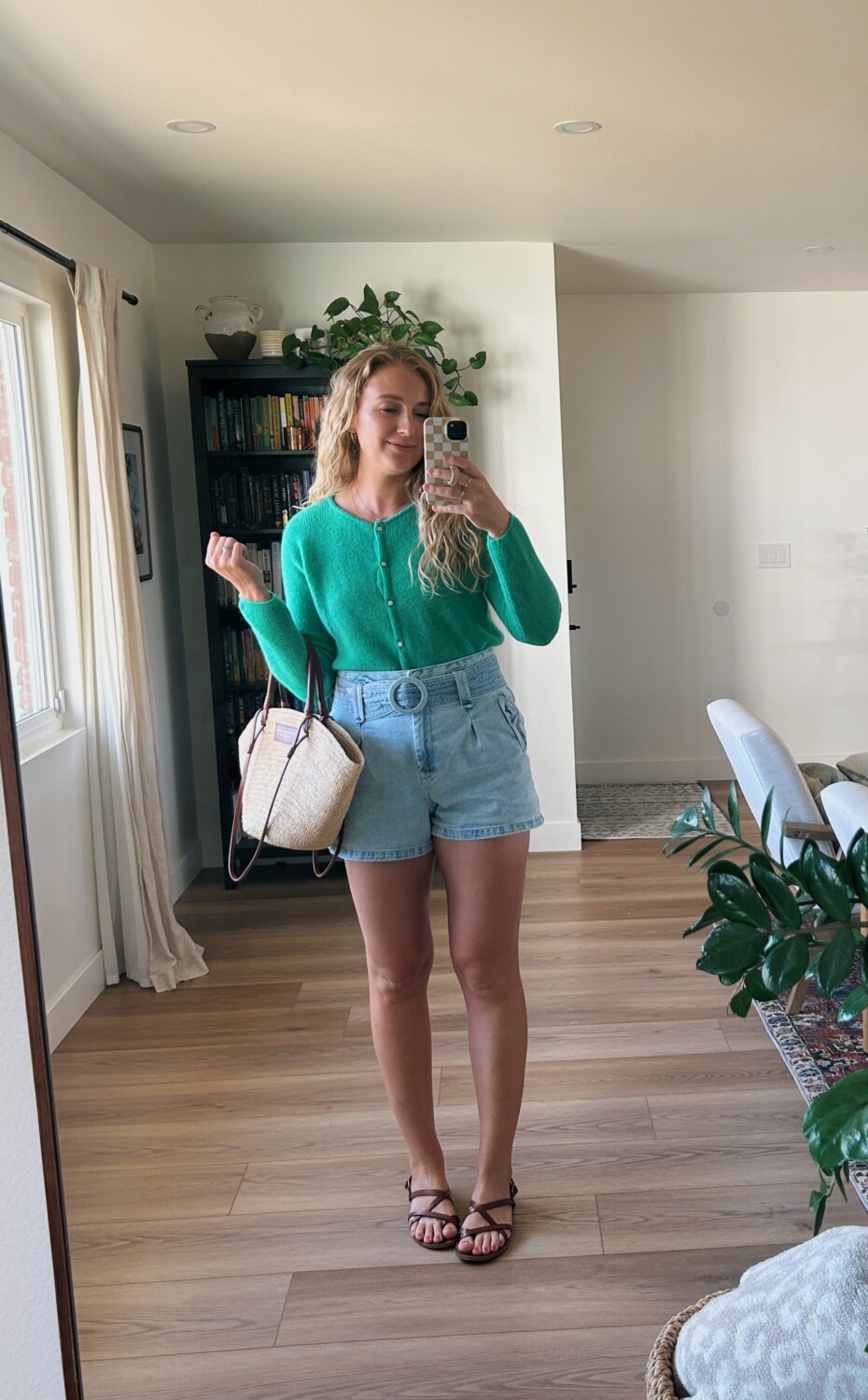 ruth nuss wearing her green gaspard cardigan from sezane tucked into belted jean shorts 