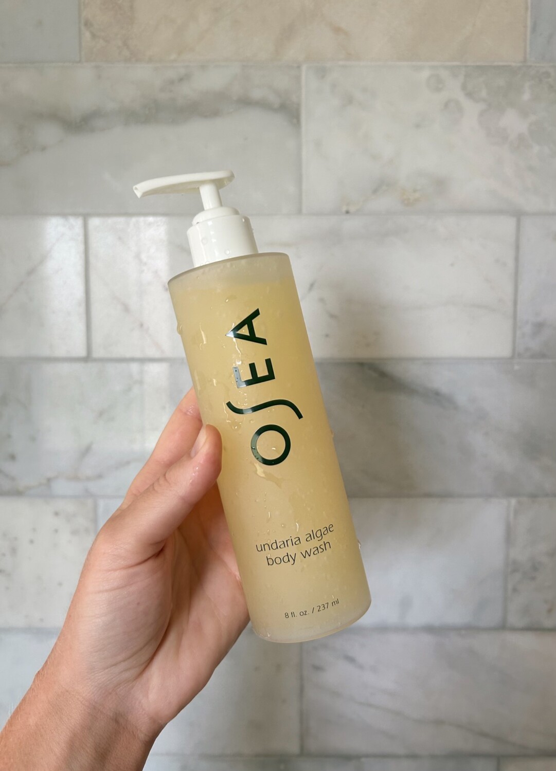 hand holding up an osea body wash for an osea body wash review