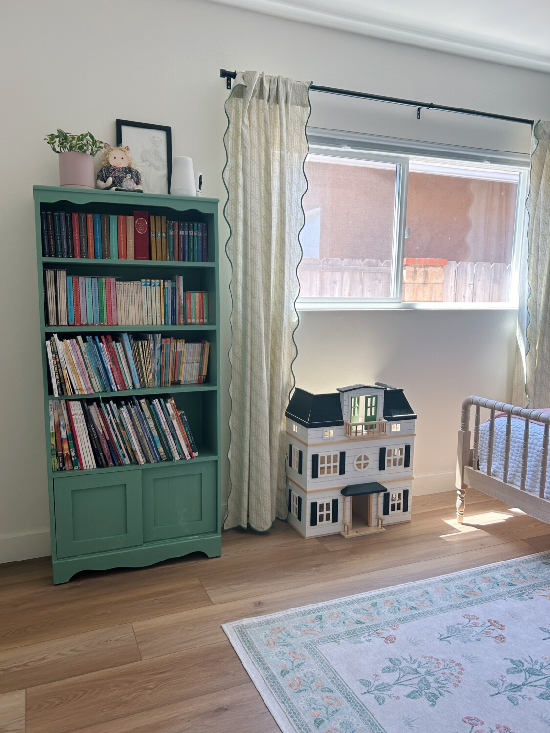 a green bookshelf next to a white and black dollhouse