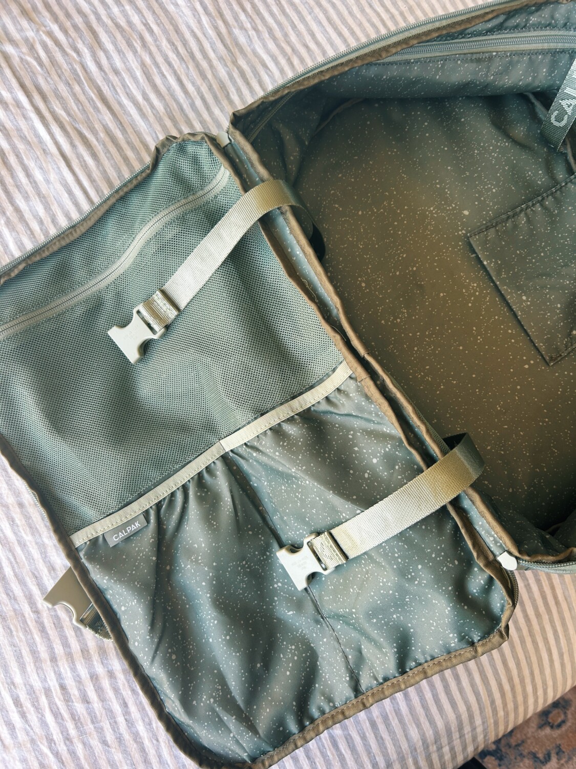 the calpak terra backpack opened up on a bed