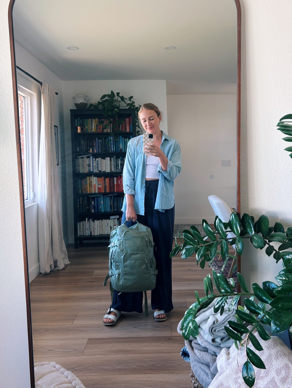 ruth nuss holding her calpak terra backpack in juniper green