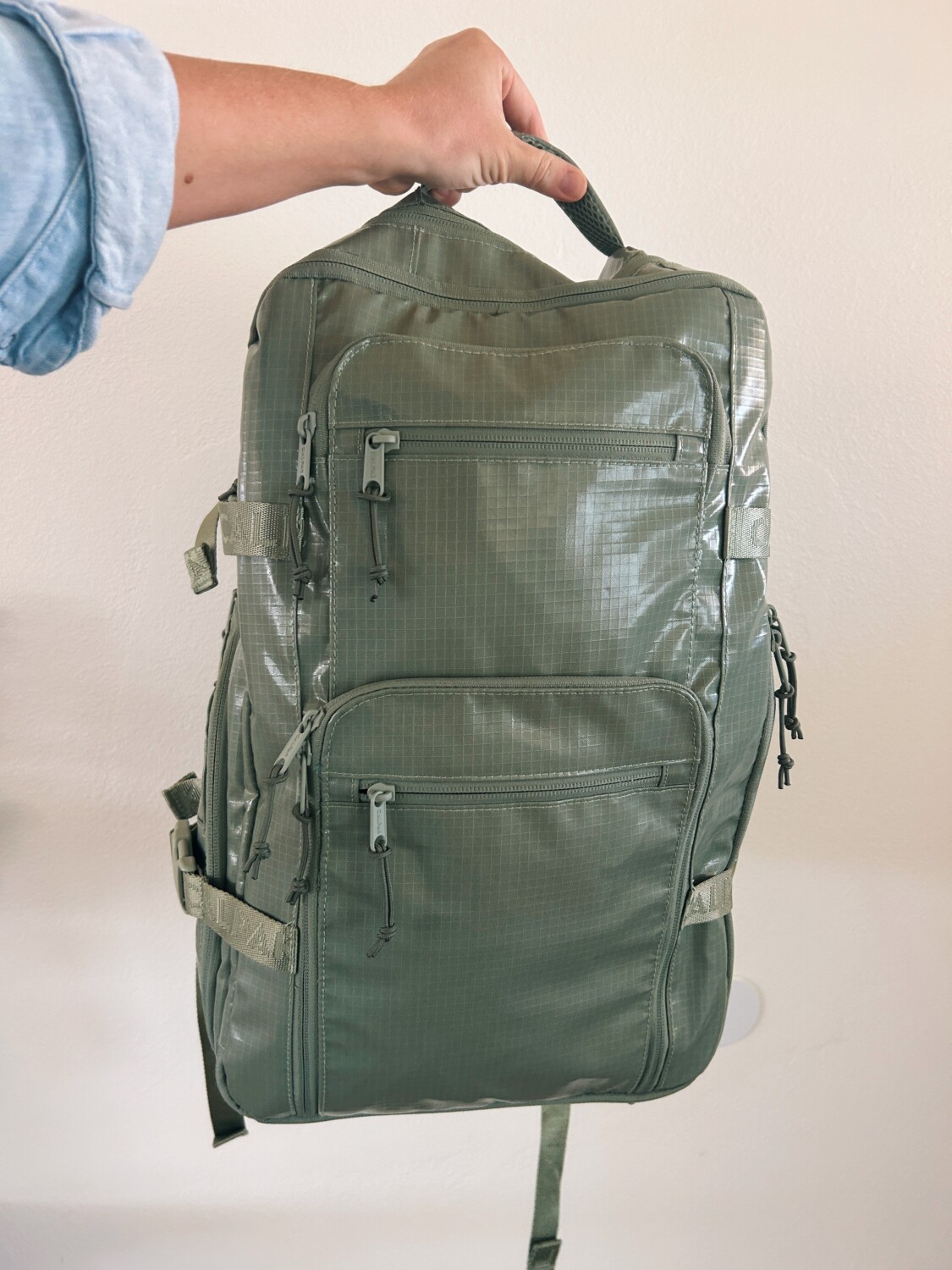 a hand holding the top of calpak terra backpack