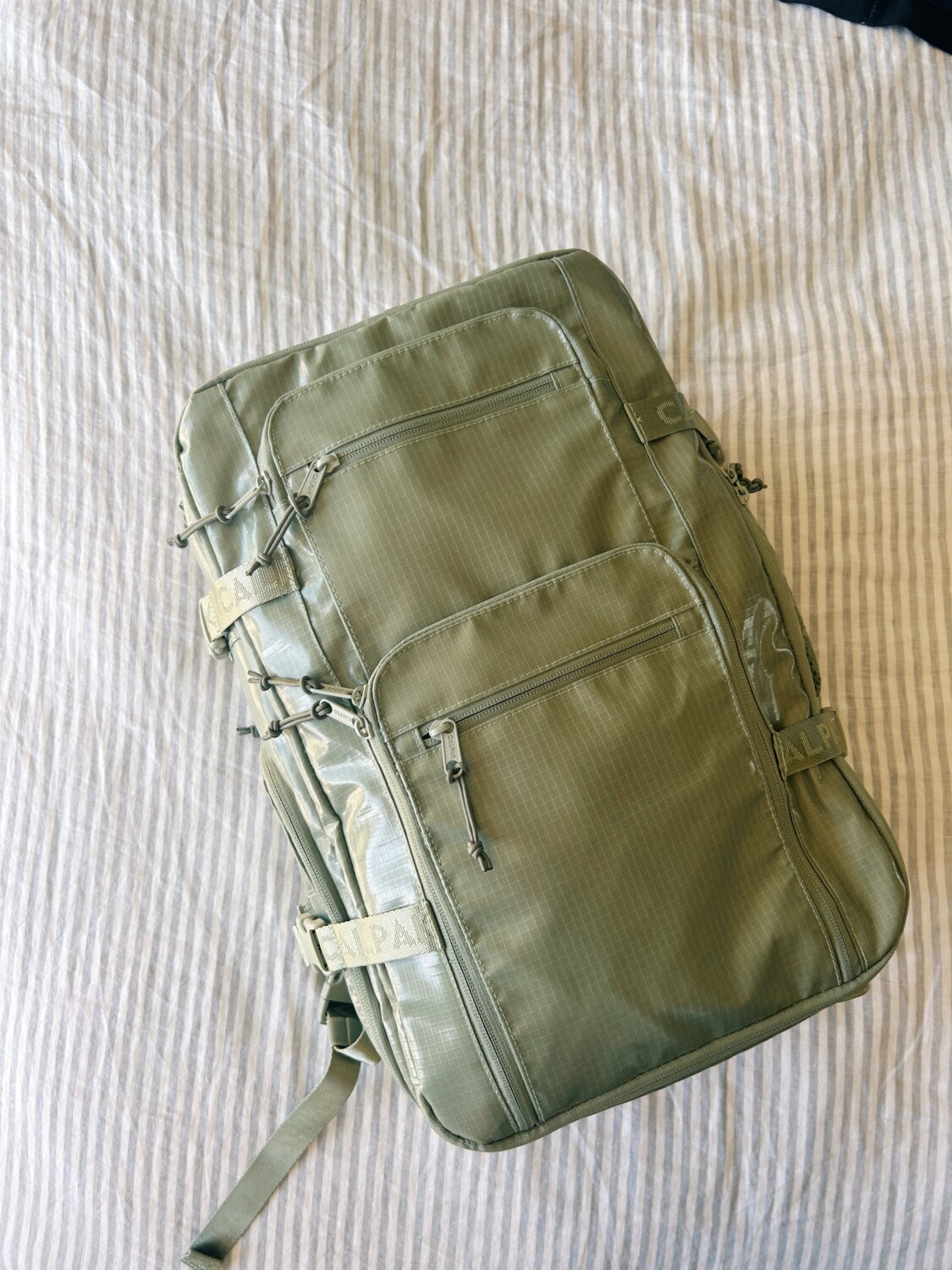 a green calpack terra duffel backpack on a bed