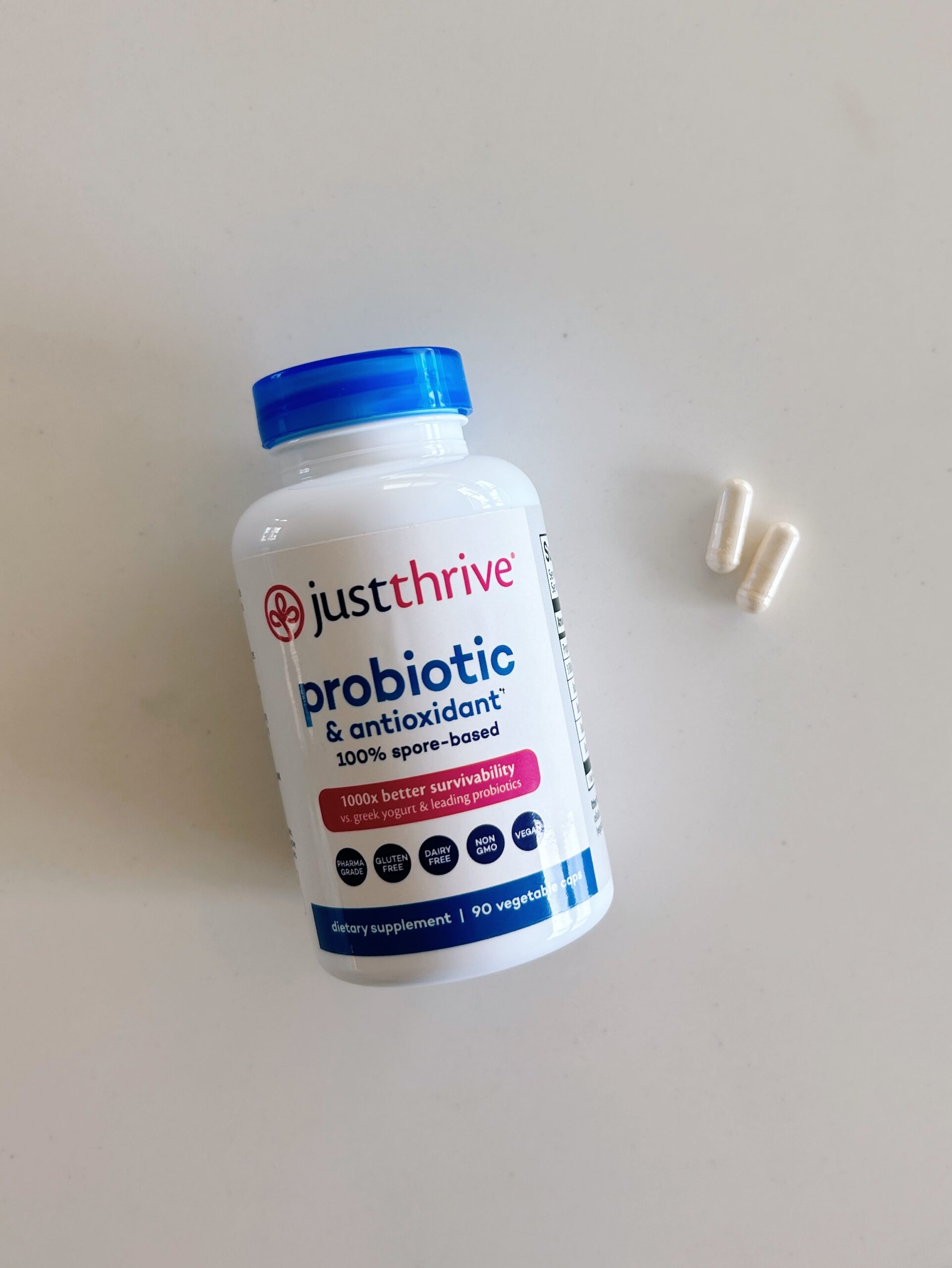 a bottle of just thrive probiotics and two white capsules