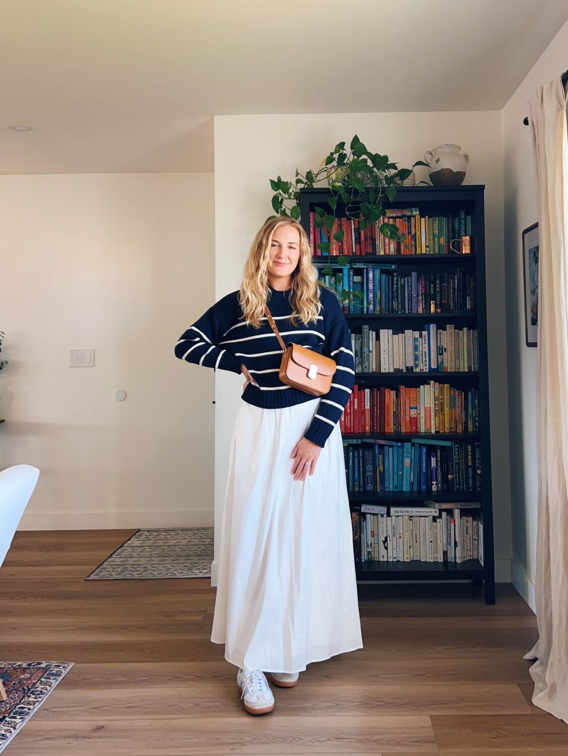 Ruth nuss wearing a navy and white striped sweater with a white maxi skirt and her golden sezane mini milo bag. white maxi skirt outfit ideas