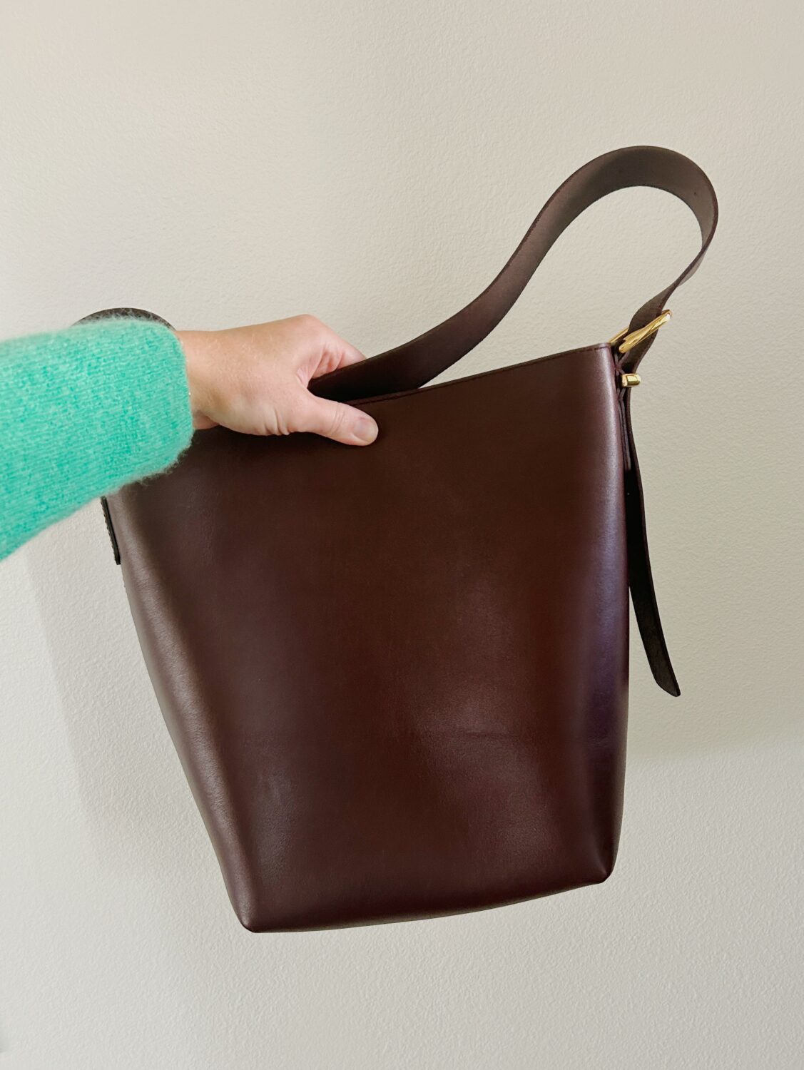 a hand holding madewell's essential medium bucket tote