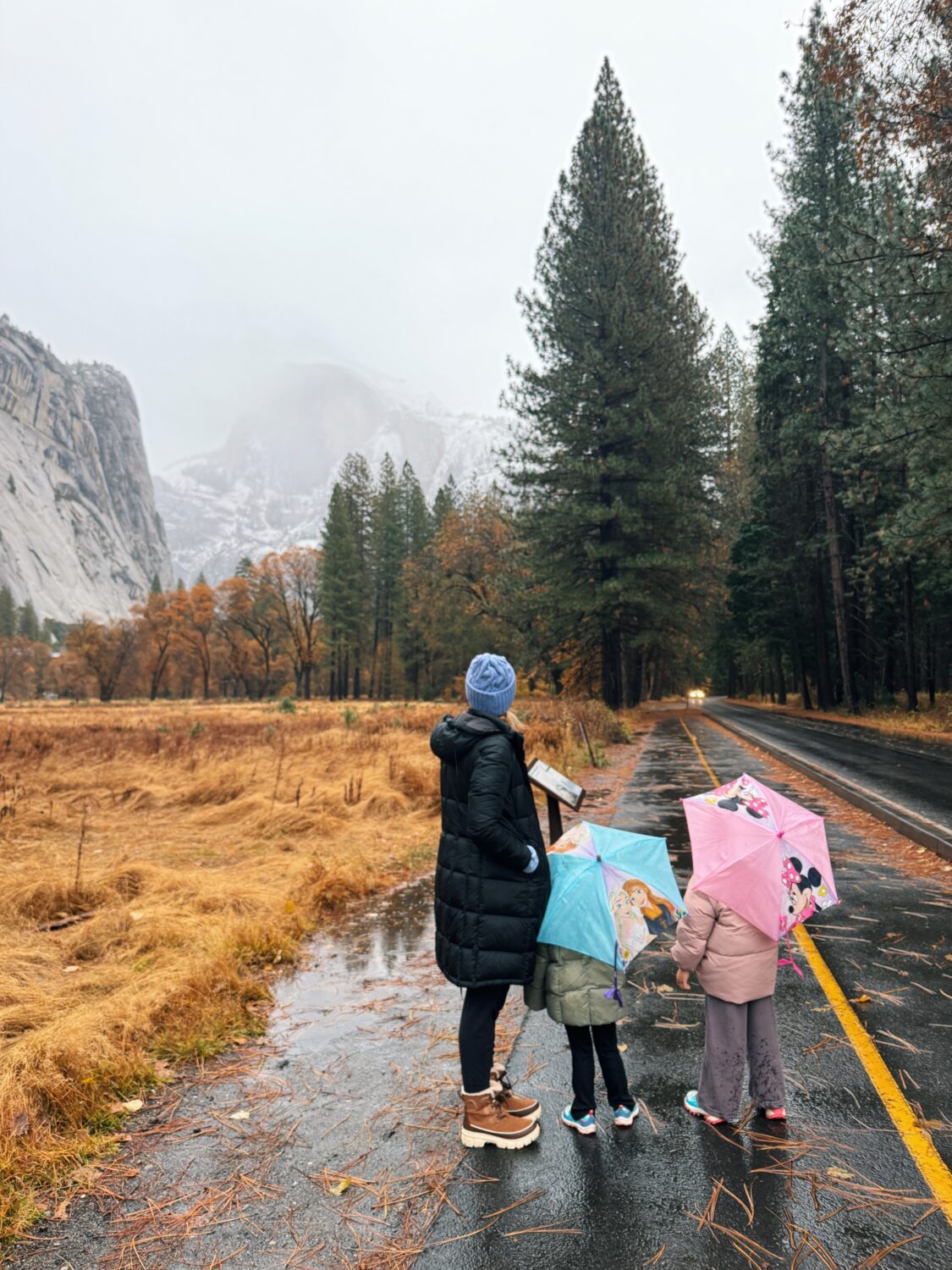 a woman and her two daughers looking at half dome in the rain. yosemite travel guide