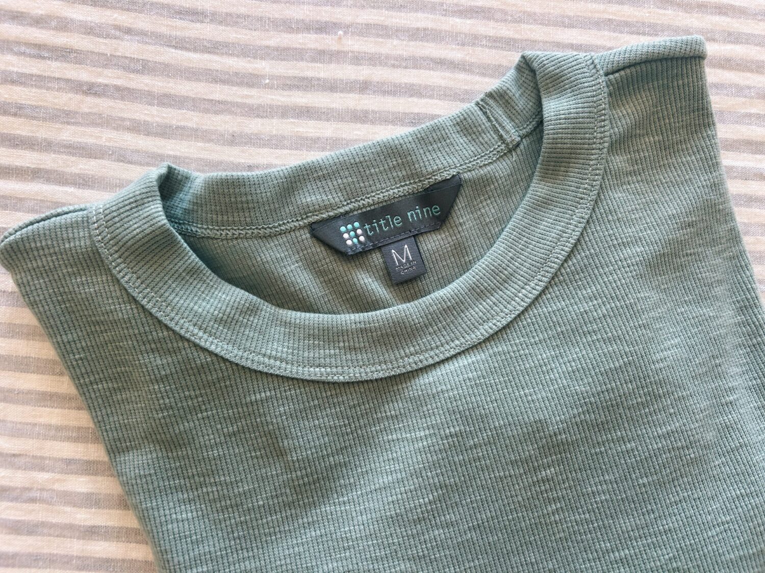 a closeup of a green title nine long sleeve shirt for a title nine clothing review