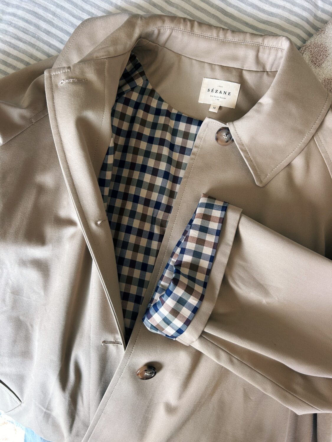 a closeup of sézane's clyde trench coat with its checked lining and collar