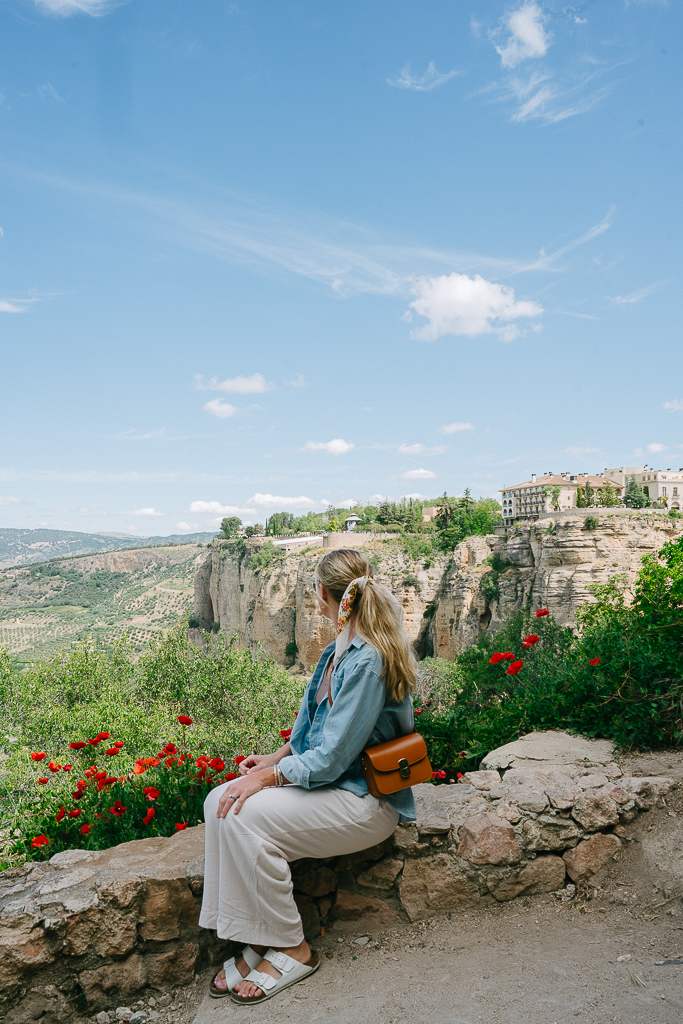 ruth nuss wearing white pants and a denim shirt in ronda spain for her summer packing list for europe