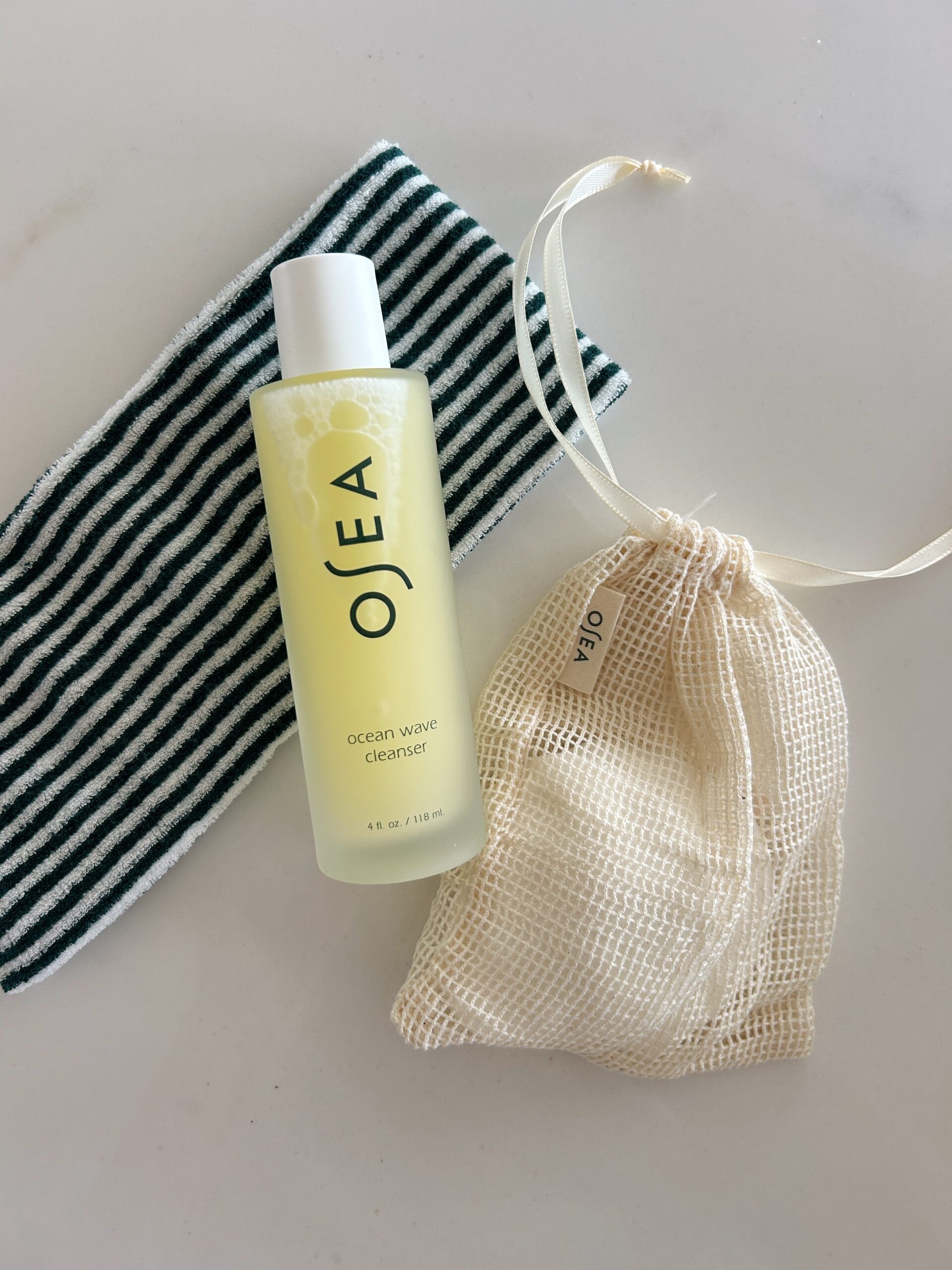 a green and white striped headband and a bottle of osea ocean wave cleanser