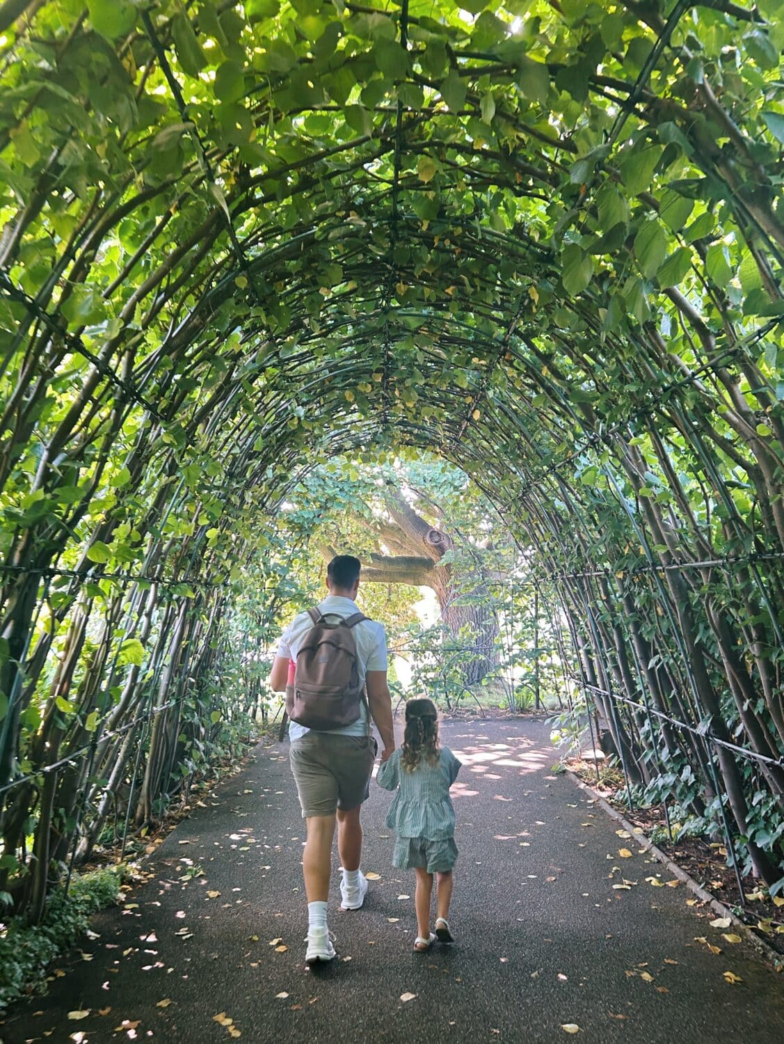 a girl and her father walking in the diana sunken memorial pond in kensington gardens in london