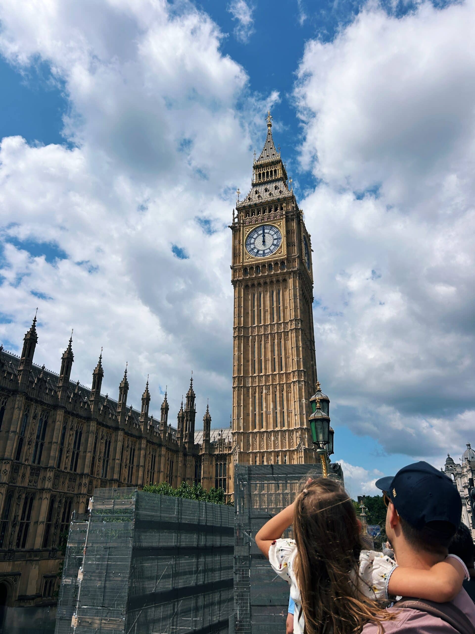 a little girl and her father looking up at big ben in london england