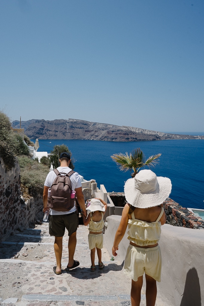 a man and his daughters walking down to ammoudi bay in oia santorini