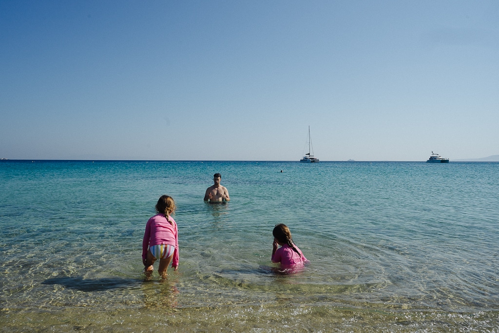 two girls and their father swimming at a beach in naxos greece . greek islands itinerary