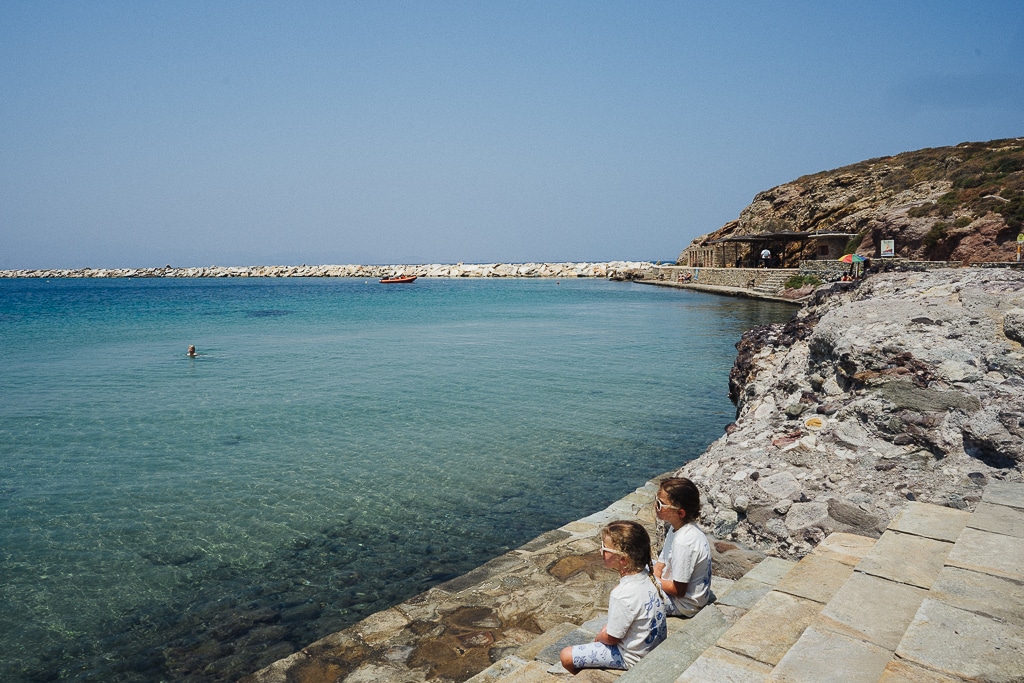 two girls sitting near the water in naxos greece. greek islands with kids
